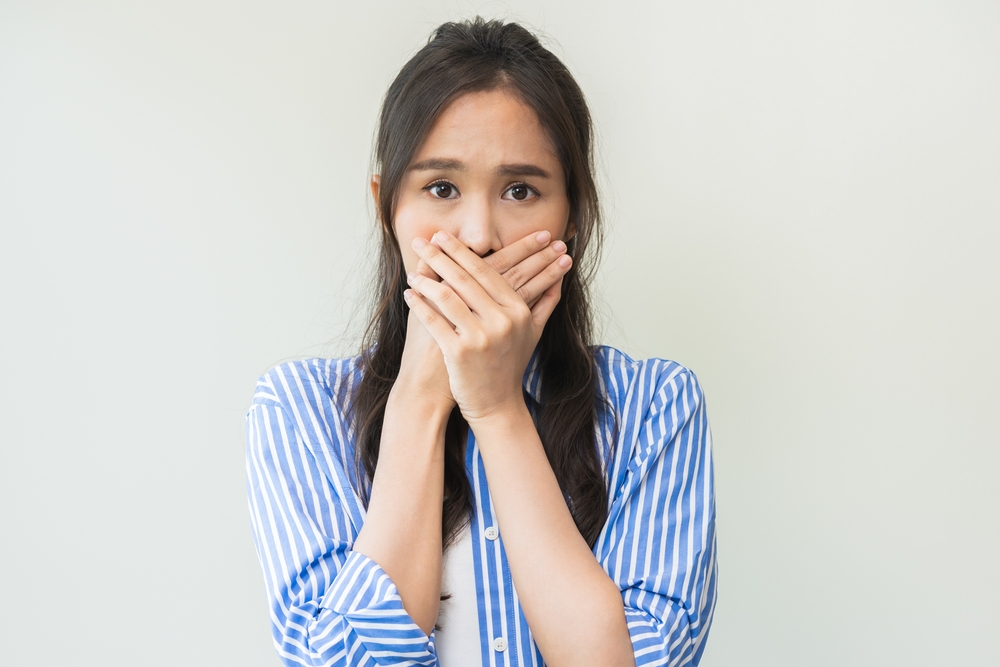 Concerned woman covering her mouth, expressing anxiety about dental pain or emergency, relevant to urgent dental care at Littleton Advanced Dentistry.